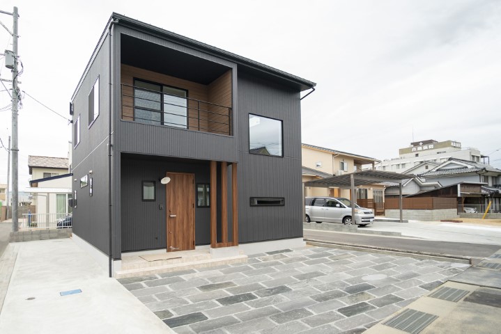 黒の外壁と木目バルコニーが調和した住宅外観